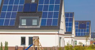 Na imagem, quatro residências equipadas com painéis solares. Na primeira casa, mostrada mais à frente, um pequeno playground para crianças se faz presente.