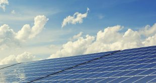 Fotografia mostra painel solar fotovoltaico com céu com nuvens ao fundo.